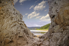 The beach is visible through the stone cliffs